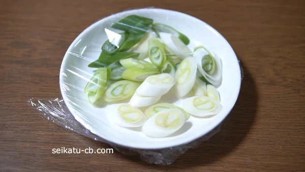 斜め切りにした長ねぎを皿に入れてラップをする