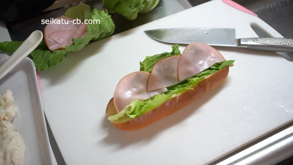 コッペパンに切ったハムをはさむ
