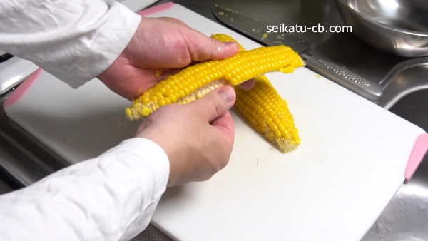縦半分にカットしたとうもろこしの粒を倒して外す