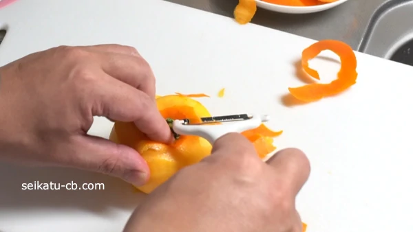 柿をまな板において上の皮をピーラーでむく