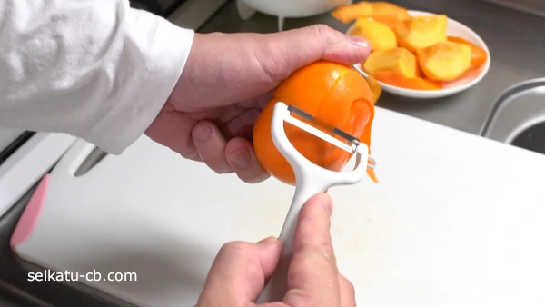 ピーラーで柿の皮をむく