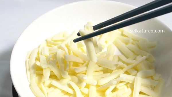 箸でつまんだ冷凍したピザ用チーズ