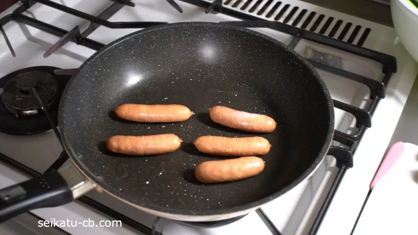 切込みを入れたウインナーをフライパンで焼く