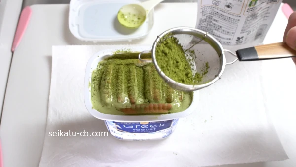 バタービスケットをさした抹茶ヨーグルトに抹茶粉末をふりかける