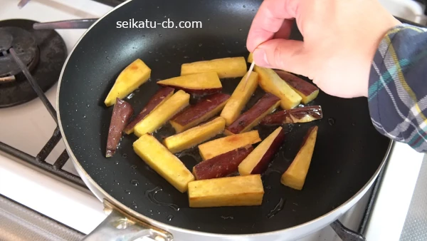 さつまいもスティックにつまようじをさして火の通りを確認する